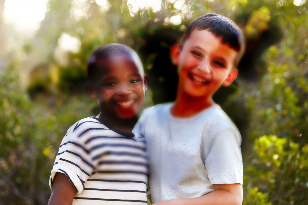 Two boys in front of a stand of trees. Random large areas of the picture obscure details as if the image has been tinted  black in those spots.
